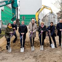 Menschen mit Spaten feiern Baubeginn