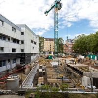 Baustelle mit Gebäuden und Kran und Bauzaun