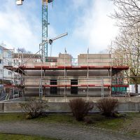 Baustelle mit großen Baukränen und Gerüst vom Gehweg