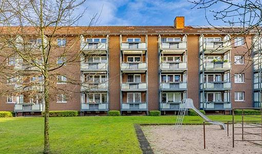 Mehrfamilienhaus in Kronshagen mit Spielplatz auf Grünfläche.