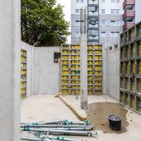 Rohbau mit gelben Gerüsten und zwei Betonpfeilern