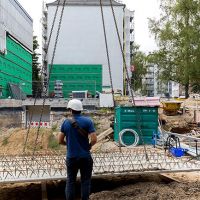 Bauarbeiter nimmt Betonplatte vom Kran an