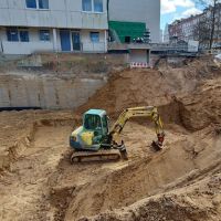 Kleiner Bagger in großer Baugrube