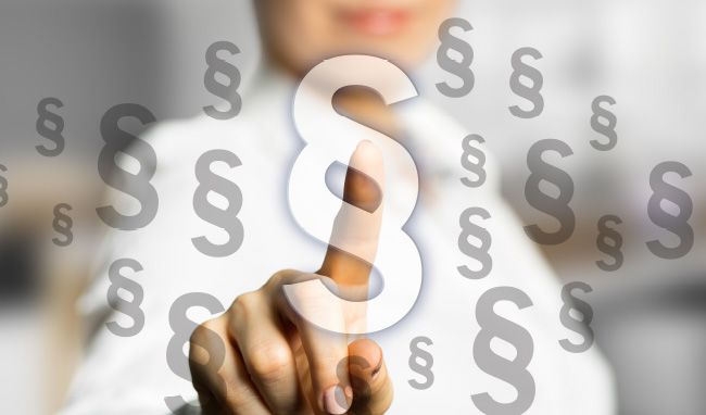 Hand mit Paragraphensymbolen im Hintergrund