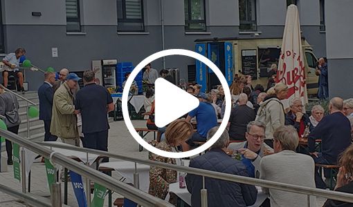 Menschenmenge beim Fertigfest vor Neubauten mit Bierbänken und Ballons.