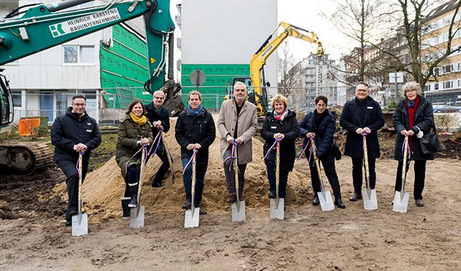 Menschen mit Spaten feiern Baubeginn